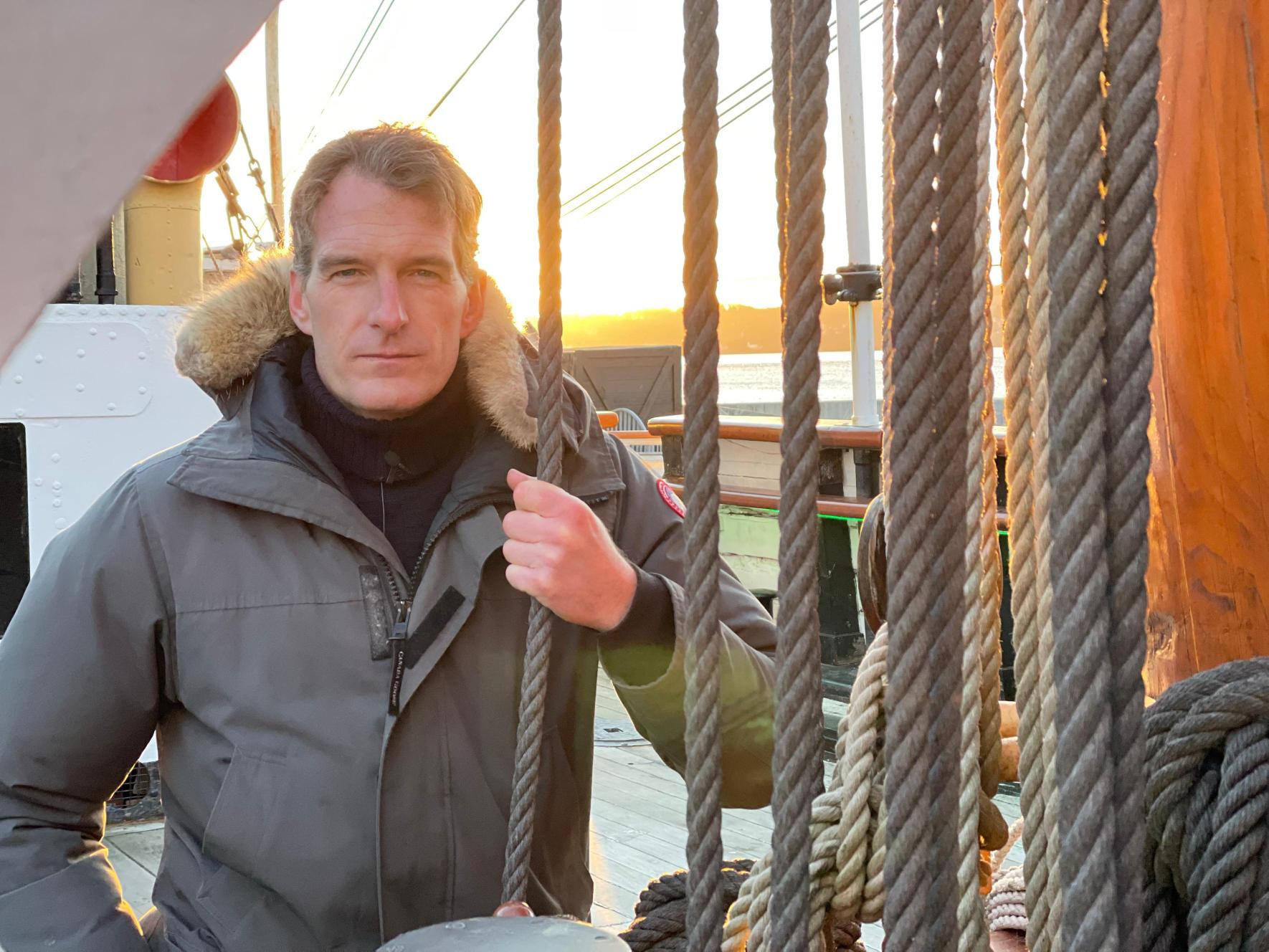 Dan Snow, wearing a grey parka and holding a rope aboard RRS Discovery
